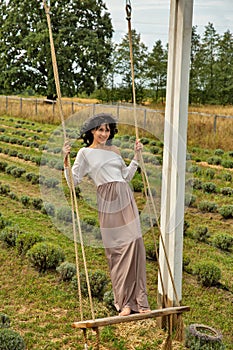 Beautiful young caucasian woman swinging on a wooden swing