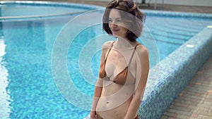 beautiful young caucasian woman on vacation resting in a hotel with a swimming pool, walking outdoors, holding a straw