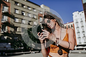 Beautiful young caucasian woman walking at the city street on a sunny day. Talking on mobile phone. Happy face smiling. Urban life