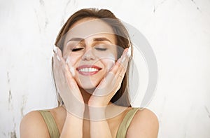 Beautiful young caucasian woman washing her face with foam