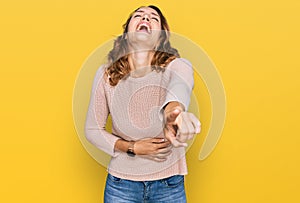 Beautiful young caucasian woman wearing casual sweater laughing at you, pointing finger to the camera with hand over body, shame