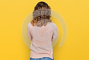 Beautiful young caucasian woman wearing casual sweater standing backwards looking away with crossed arms