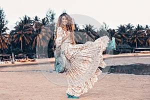 Beautiful young cheerful fashion model in white dress with guitar having fun outdoors at sunset