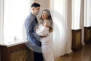 Beautiful young couple bride and groom hugging near the window