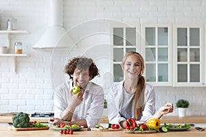 Beautiful young couple cooking vegetable salad while standing in the kitchen at home, enjoying time together. Healthy lifestyle