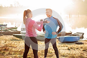 Wide aspect ratio photo of beautiful young couple exercising and stretching by the river or lake