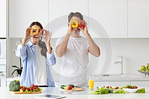 Beautiful young couple having fun while cooking healthy food in kitchen at home