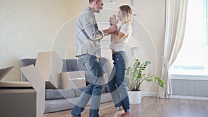 Beautiful young couple having fun dancing at new apartment, celebrating moving to a new home