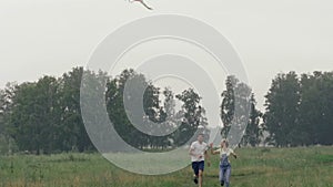 Beautiful young couple having fun in a forest glade, launching a kite