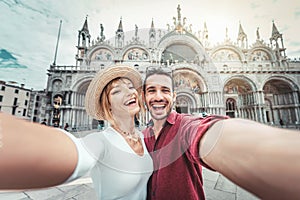 Beautiful young couple having fun visiting Venice - Tourists enjoying holiday in Italy taking selfie