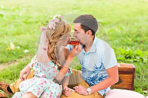 Beautiful Young Couple Having Picnic in Countryside. Happy Family Outdoor. Smiling Man and Woman relaxing in Park