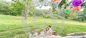 Beautiful Young Couple Having Picnic in Countryside. Happy Family Outdoor. Smiling Man and Woman relaxing in Park