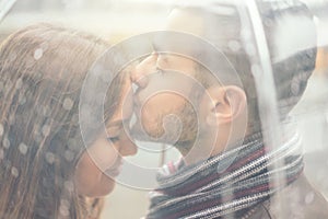 Beautiful young couple having a romantic tender moment under the rain - Handsome man kissing his girlfriend forehead