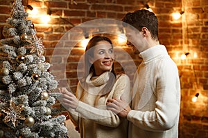 Beautiful young couple at home decorating a Christmas tree. Spending time together, relationships and people concept