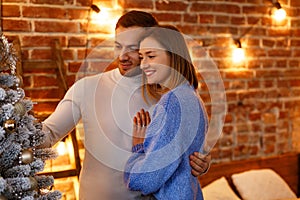 Beautiful young couple at home decorating a Christmas tree. Spending time together, relationships and people concept