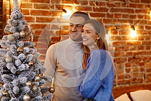 Beautiful young couple at home decorating a Christmas tree. Spending time together, relationships and people concept