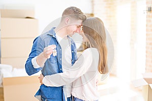 Beautiful young couple hugging in love and showing keys of new house, smiling happy moving to a new apartment