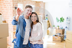 Beautiful young couple hugging in love and showing keys of new house, smiling happy moving to a new apartment