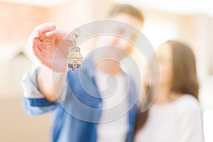 Beautiful young couple hugging in love and showing keys of new house, smiling happy moving to a new apartment