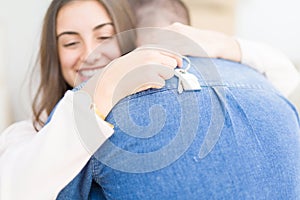 Beautiful young couple hugging in love and showing keys of new house, smiling happy moving to a new apartment