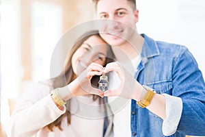 Beautiful young couple hugging in love and showing keys of new house, smiling happy moving to a new apartment