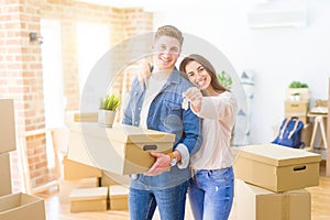Beautiful young couple hugging in love and showing keys of new house, smiling happy moving to a new apartment