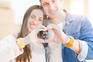 Beautiful young couple hugging in love and showing keys of new house, smiling happy moving to a new apartment