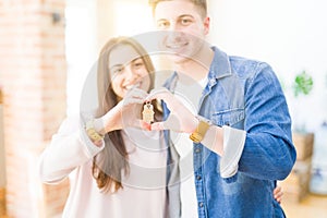 Beautiful young couple hugging in love and showing keys of new house, smiling happy moving to a new apartment