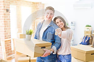 Beautiful young couple hugging in love and showing keys of new house, smiling happy moving to a new apartment