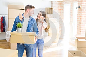 Beautiful young couple hugging in love and showing keys of new house, smiling happy moving to a new apartment