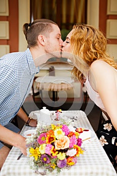 A beautiful young couple is kissing in a cafe. Summer vacation with your beloved