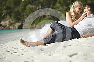 Beautiful young couple kissing on sunset lying on sand, sunset t