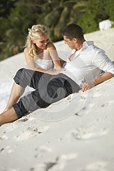 Beautiful young couple kissing on sunset lying on sand, sunset t