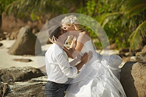 Beautiful young couple kissing on sunset, standing barefoot on b