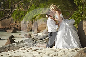 Beautiful young couple kissing on sunset, standing barefoot on b