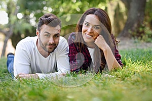 Beautiful young couple laying on grass in an urban park.