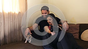 Beautiful young couple in the living room relaxing and playing with their cats