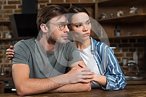 Beautiful young couple in loungewear sitting by table