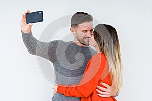 Beautiful young couple in love, kissing and hugging each other taking a selfie picture