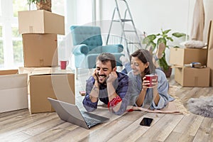 Couple searching the Web for apartment redecoration ideas while moving in together photo