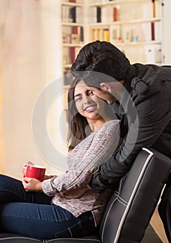 Beautiful young couple in love in st valentines day, man hugging his girlfriend in a blurred office background