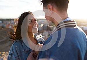 Beautiful young couple in love standing at a building rooftop at the sunset.