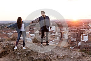 Beautiful young couple in love standing at a building rooftop at the sunset.