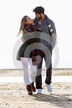 Beautiful young couple in love walking in a cold winter on the b