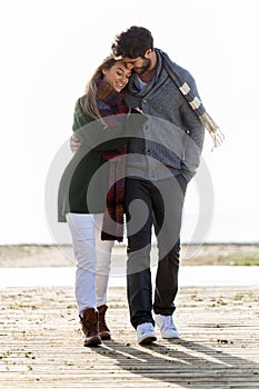 Beautiful young couple in love walking in a cold winter on the b