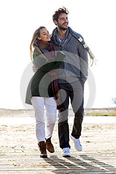 Beautiful young couple in love walking in a cold winter on the b