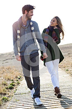 Beautiful young couple in love walking in a cold winter on the b