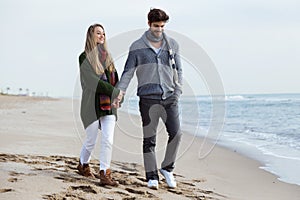 Beautiful young couple in love walking in a cold winter on the b