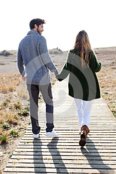 Beautiful young couple in love walking in a cold winter on the b