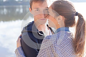 Beautiful young couple in love walking on the shore of the lake at sunset in the rays of bright light